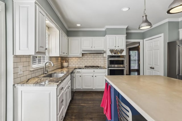 kitchen with a sink, appliances with stainless steel finishes, white cabinets, ornamental molding, and under cabinet range hood