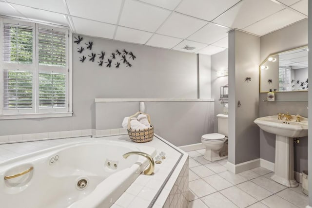 bathroom featuring a whirlpool tub, toilet, tile patterned flooring, baseboards, and a paneled ceiling