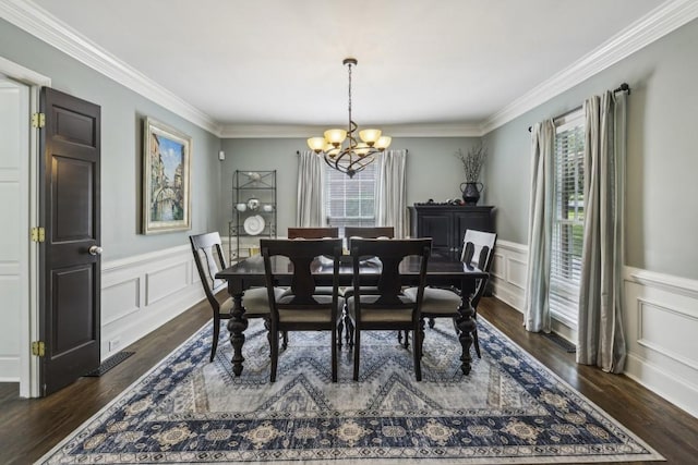 dining area with healthy amount of natural light, a chandelier, a decorative wall, ornamental molding, and dark wood-type flooring