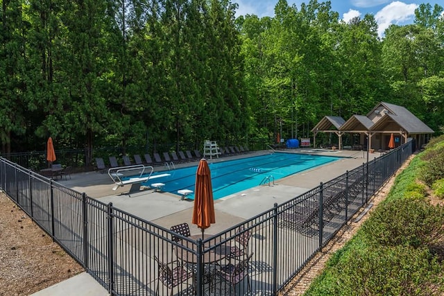 community pool featuring fence, a patio area, and a diving board