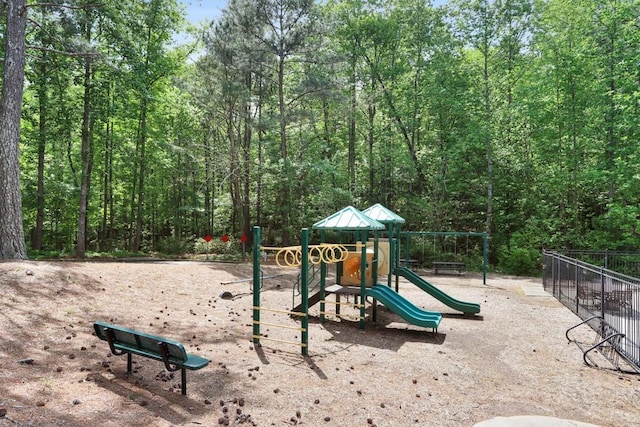 communal playground with fence and a forest view