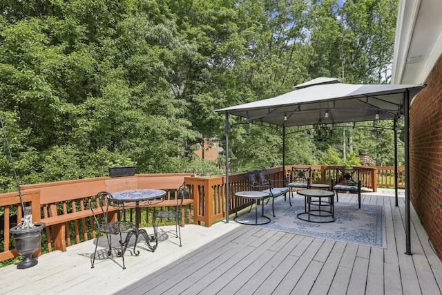 deck featuring a gazebo, outdoor dining area, and view of scattered trees