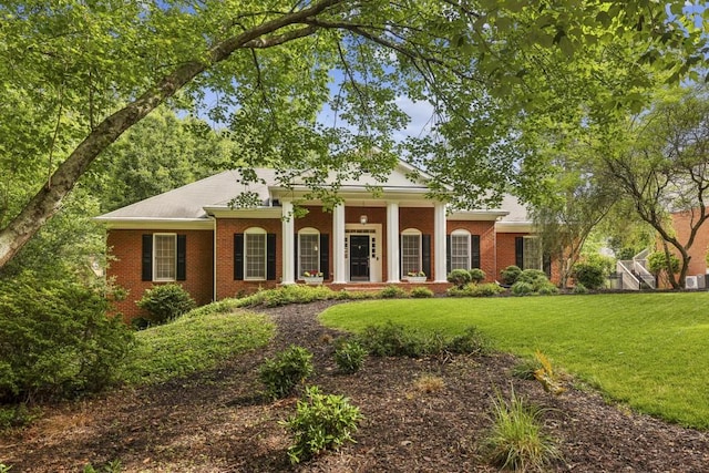 greek revival house featuring a front lawn, brick siding, and covered porch