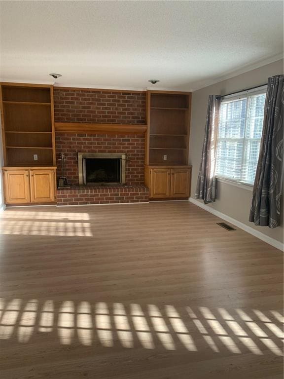 240 W Huntington Rd, Bogart, GA 30622 - unfurnished living room featuring baseboards, light wood-type flooring, a textured ceiling, a fireplace, and built in shelves