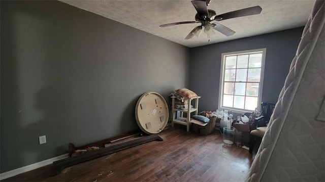 miscellaneous room with dark wood-type flooring, ceiling fan, and a textured ceiling