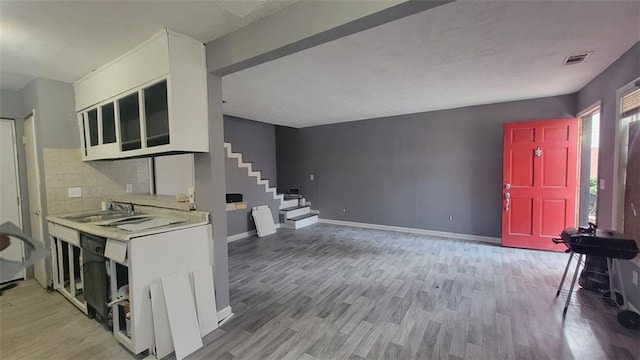 kitchen with tasteful backsplash, sink, light hardwood / wood-style flooring, and white cabinets