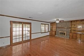 unfurnished living room with a ceiling fan, baseboards, wood finished floors, and a fireplace