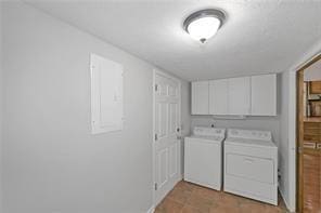 clothes washing area featuring separate washer and dryer, cabinet space, and light tile patterned flooring