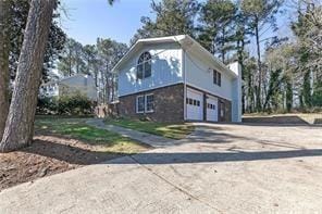 exterior space with an attached garage, a chimney, and concrete driveway