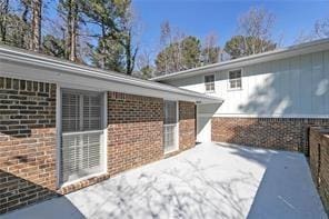 exterior space with brick siding and a patio area