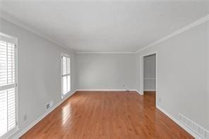 spare room with baseboards, ornamental molding, and wood finished floors