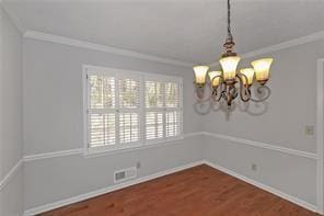 unfurnished dining area featuring visible vents, ornamental molding, wood finished floors, and a notable chandelier