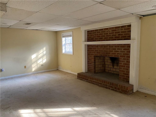 unfurnished living room featuring carpet, a brick fireplace, and a drop ceiling