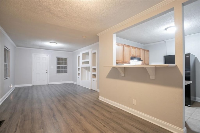 2817 Burton Rd NW, Atlanta, GA 30311 - kitchen with a textured ceiling, a breakfast bar area, light brown cabinetry, dark wood-style flooring, and crown molding