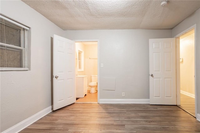 2817 Burton Rd NW, Atlanta, GA 30311 - unfurnished bedroom with wood finished floors, baseboards, a textured ceiling, and ensuite bath