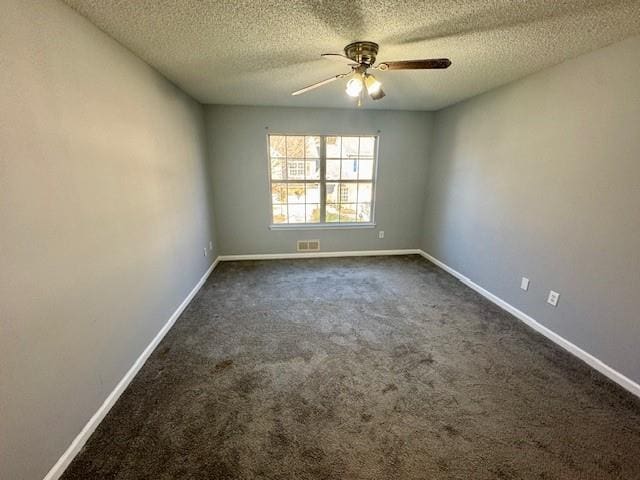 spare room with a textured ceiling, ceiling fan, dark carpet, and baseboards