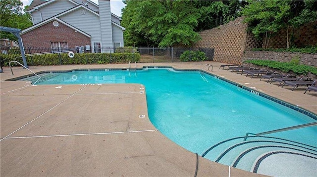 community pool with fence and a patio area