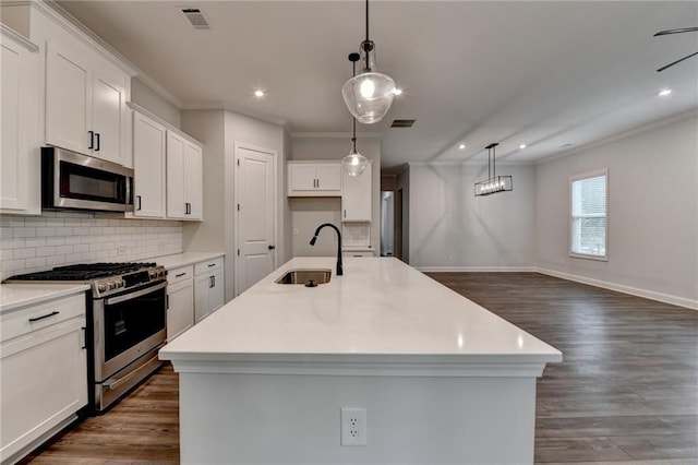 kitchen with a sink, stainless steel appliances, ornamental molding, a center island with sink, and decorative backsplash