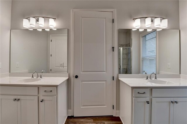 full bathroom with a stall shower, two vanities, and wood finished floors