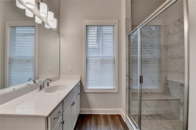 bathroom featuring baseboards, wood finished floors, a shower stall, vanity, and plenty of natural light