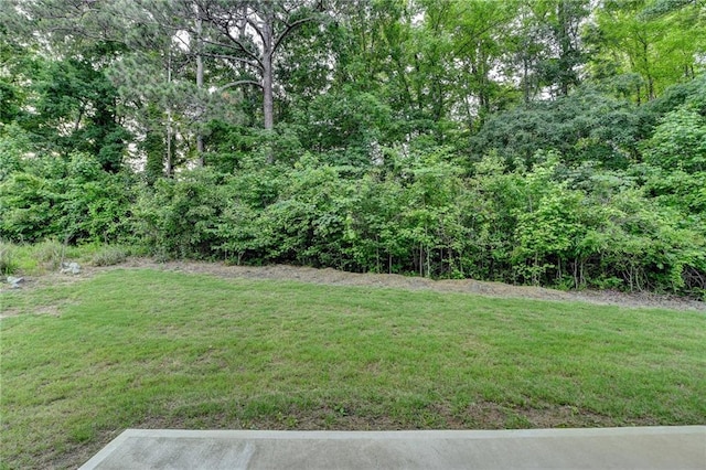 view of grassy yard featuring a view of trees