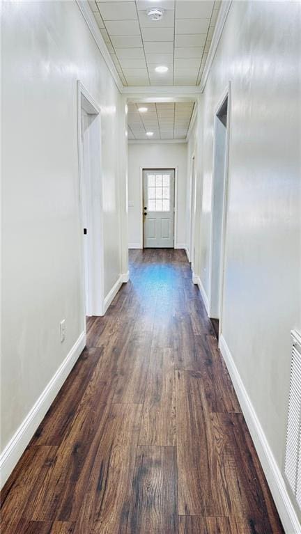 corridor featuring dark wood-style floors, a drop ceiling, visible vents, and baseboards