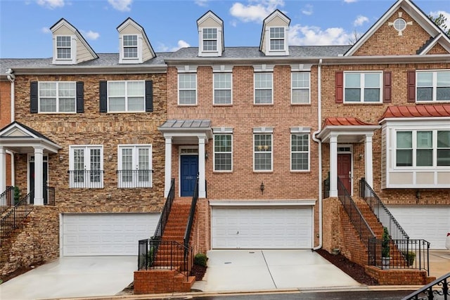 multi unit property featuring brick siding, an attached garage, concrete driveway, and stairs