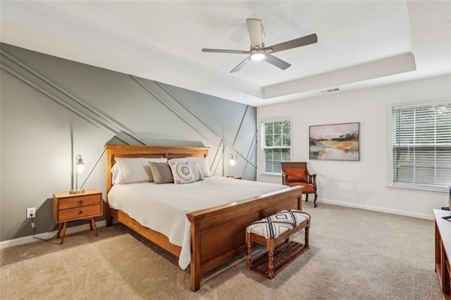 bedroom featuring a tray ceiling, light colored carpet, and baseboards