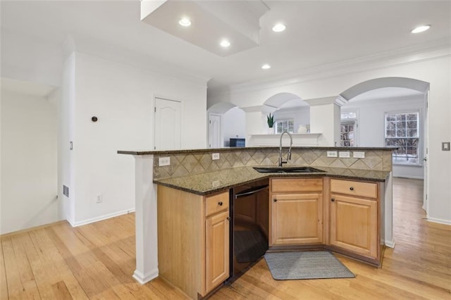 kitchen with arched walkways, decorative backsplash, dishwasher, and a sink