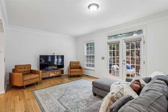 living area featuring baseboards, crown molding, light wood-style flooring, and french doors