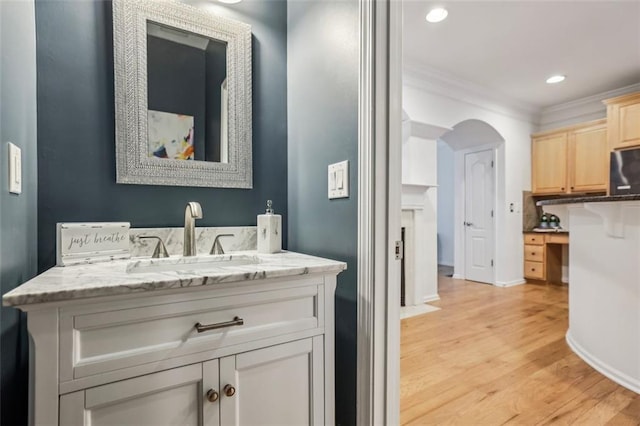 bathroom with wood finished floors, recessed lighting, crown molding, baseboards, and vanity