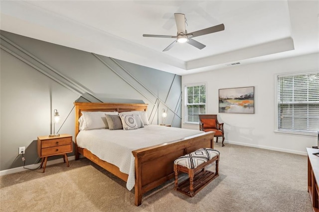 bedroom featuring baseboards, light colored carpet, and a raised ceiling