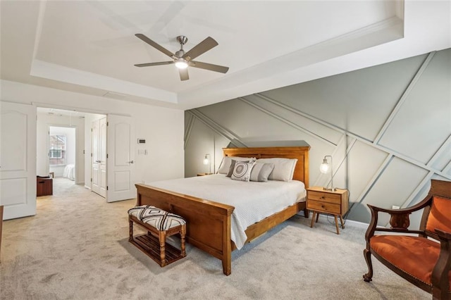 bedroom featuring a tray ceiling, light colored carpet, and a ceiling fan