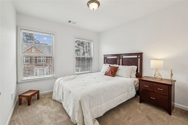 bedroom featuring baseboards, visible vents, and light carpet