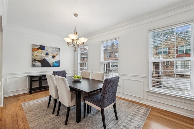dining space featuring crown molding, light wood-style flooring, and a chandelier
