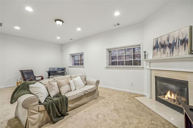 carpeted living room with a high end fireplace, recessed lighting, baseboards, and visible vents
