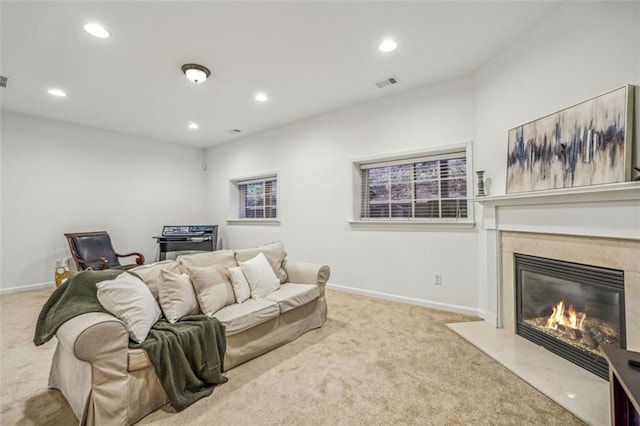 carpeted living area with visible vents, recessed lighting, baseboards, and a premium fireplace