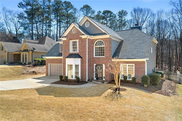 view of front of home with a front yard, fence, driveway, a chimney, and brick siding