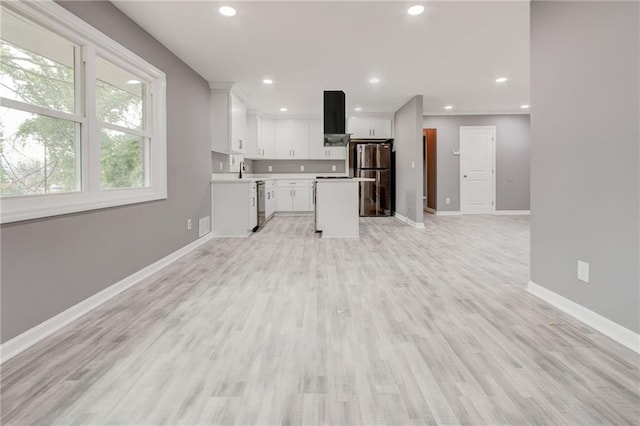 kitchen featuring sink, a center island, light wood-type flooring, stainless steel appliances, and white cabinets