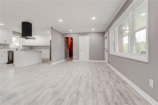 unfurnished living room with crown molding and light wood-type flooring