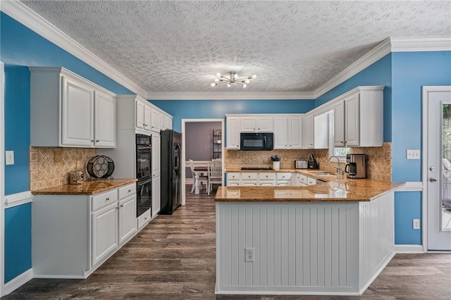 340 Chandler Ct, Sugar Hill, GA 30518 - kitchen with black appliances, dark wood-style flooring, a peninsula, a chandelier, and white cabinetry