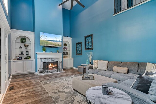 340 Chandler Ct, Sugar Hill, GA 30518 - living area with a towering ceiling, ceiling fan, wood finished floors, built in shelves, and a premium fireplace