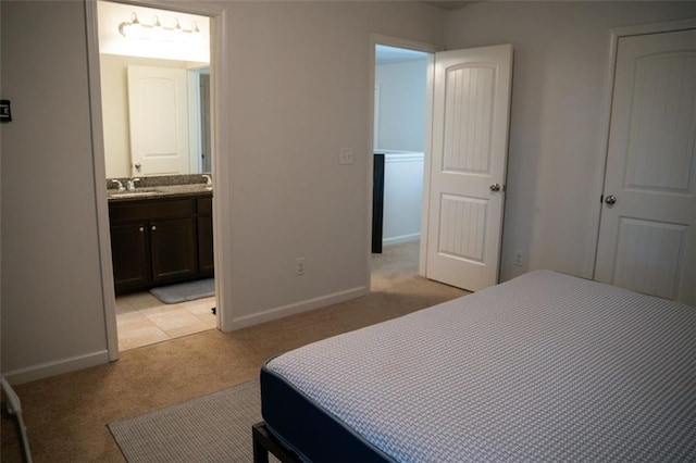 bedroom with ensuite bathroom, sink, and light carpet