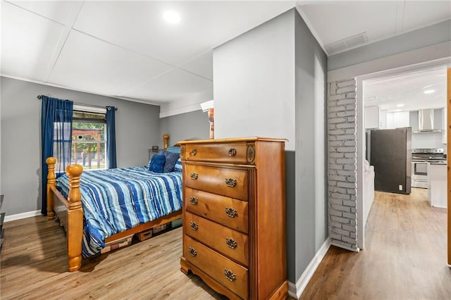 bedroom with light wood-type flooring and stainless steel refrigerator