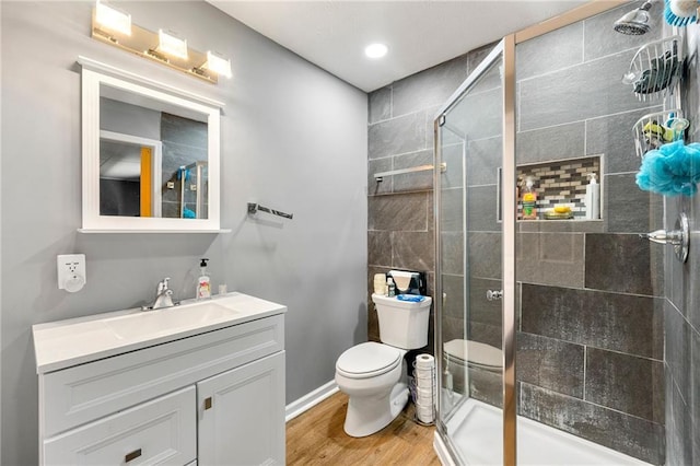 bathroom featuring wood-type flooring, toilet, walk in shower, and vanity