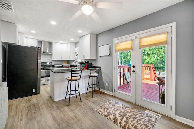 kitchen with fridge, white cabinetry, stainless steel range with electric stovetop, kitchen peninsula, and wall chimney exhaust hood