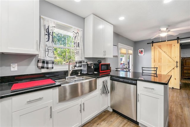 kitchen featuring kitchen peninsula, white cabinetry, dishwasher, and a barn door