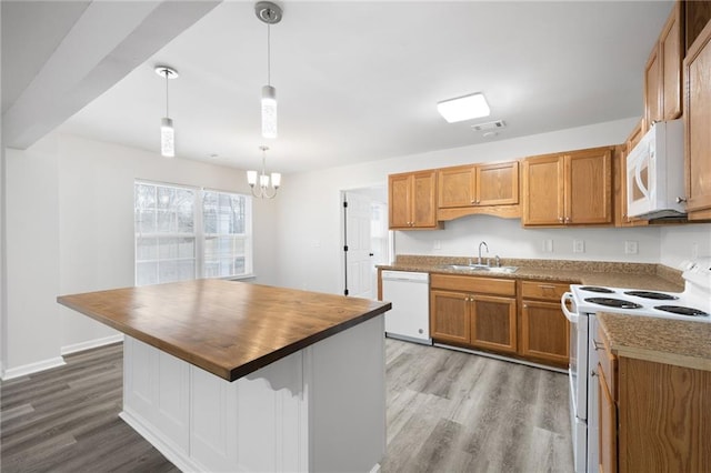 kitchen with pendant lighting, white appliances, a kitchen island, sink, and butcher block countertops