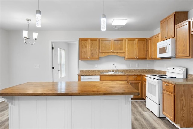 kitchen featuring sink, decorative light fixtures, white appliances, a kitchen island, and butcher block counters