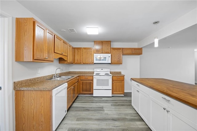 kitchen featuring pendant lighting, white appliances, white cabinets, light hardwood / wood-style floors, and sink